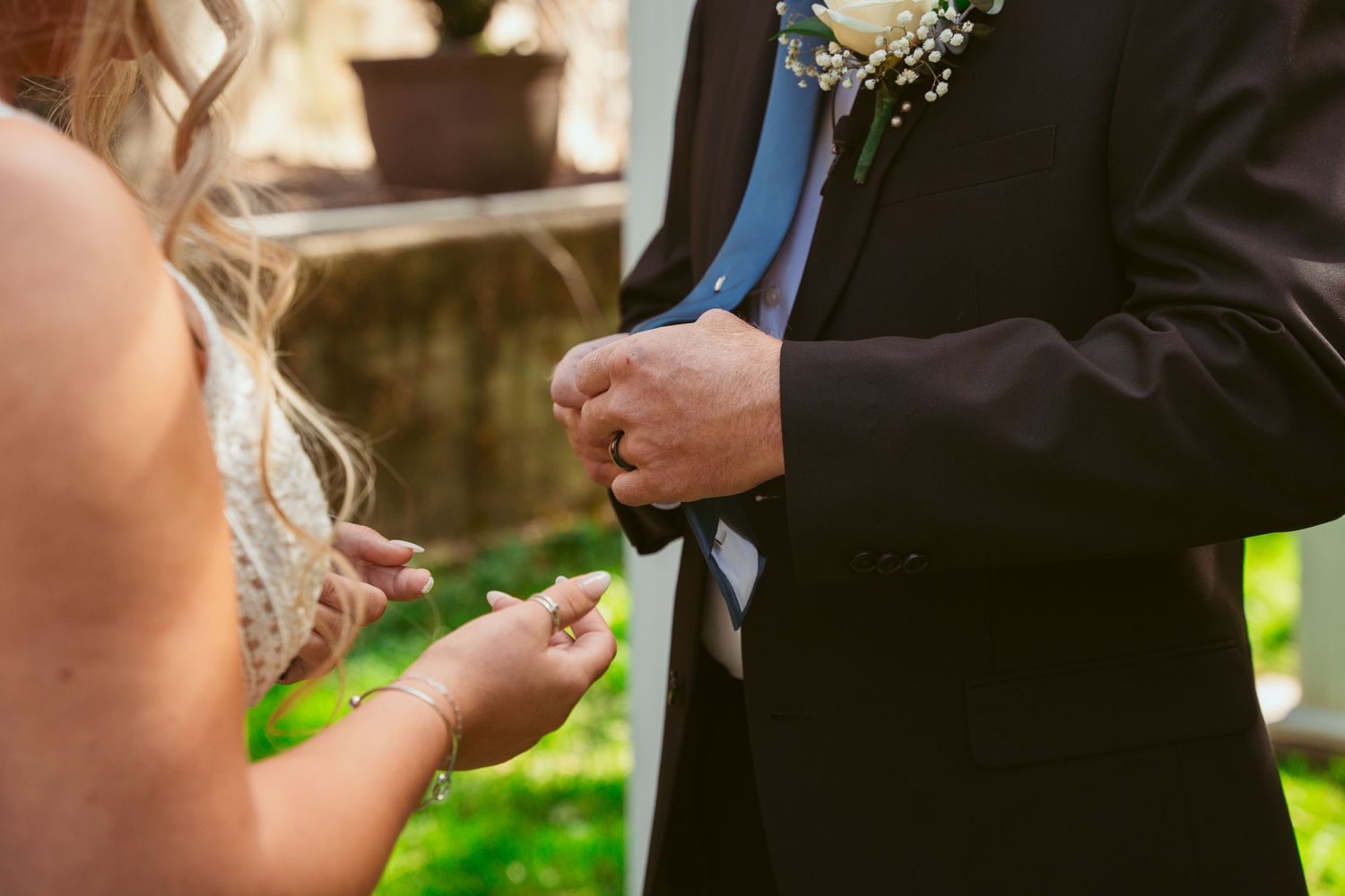 Close-up of wedding couple exchanging vows under white pergola with natural lighting.