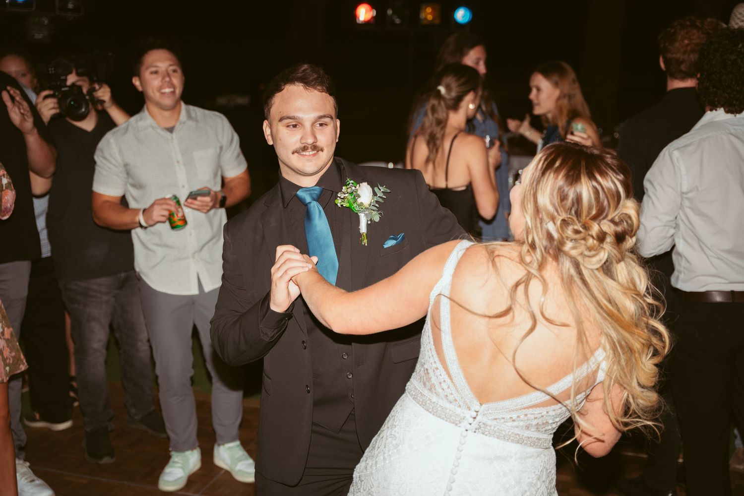 Couples dancing together at an evening wedding reception with ambient lighting.