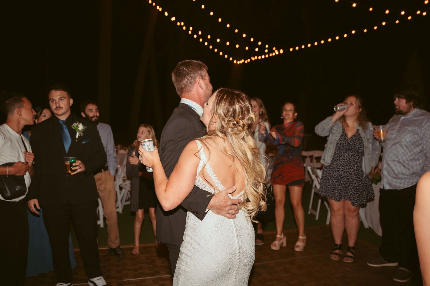 Lively dance party scene under outdoor string lights at night.