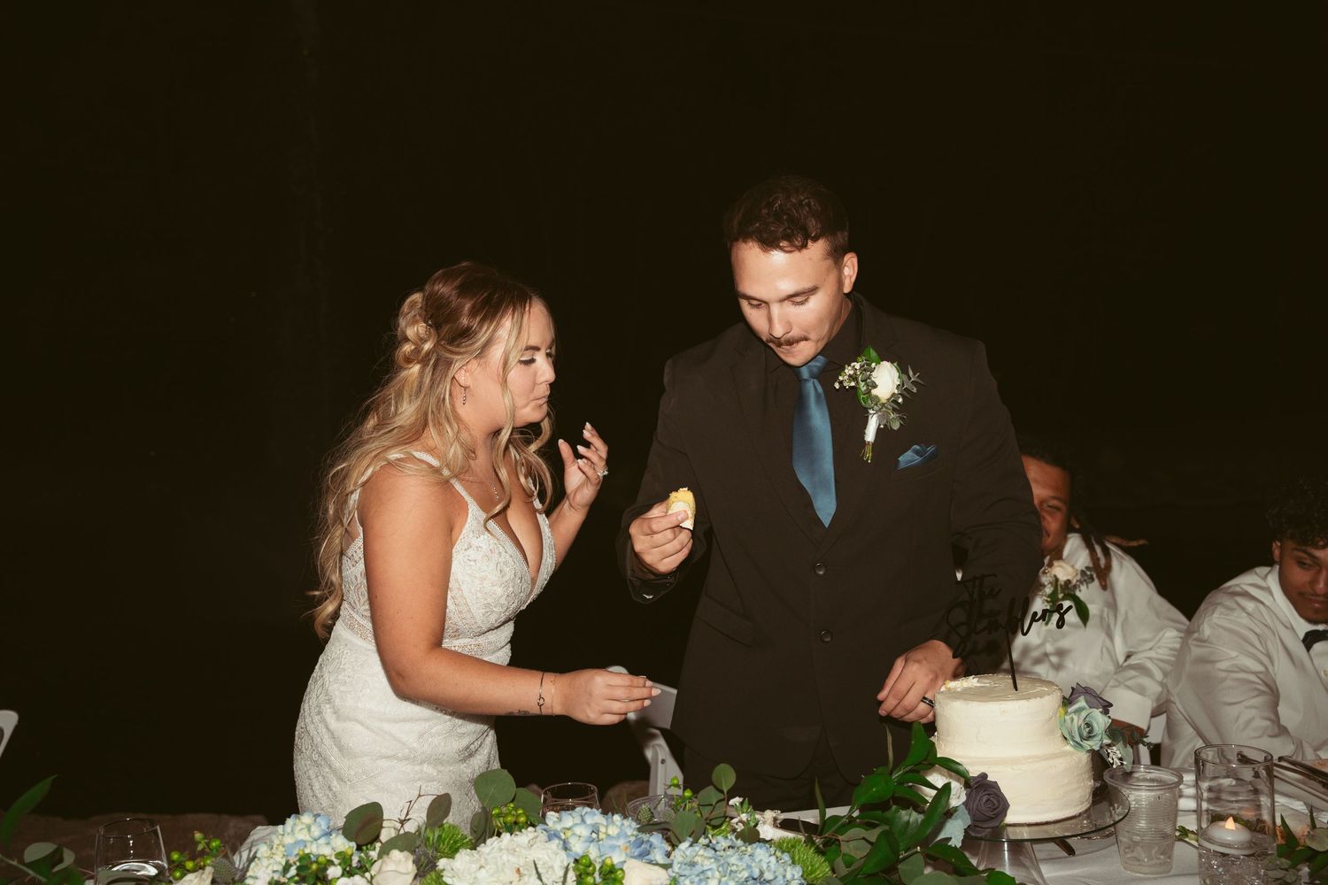 Newlyweds sharing a moment while cutting their wedding cake at the reception.