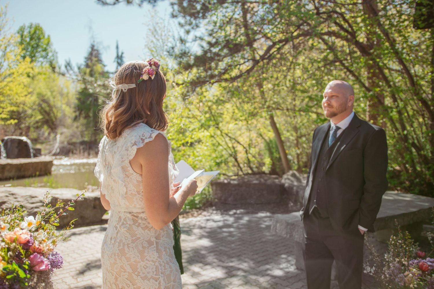 Wedding party poses outdoors in a natural garden setting on a sunny spring day.