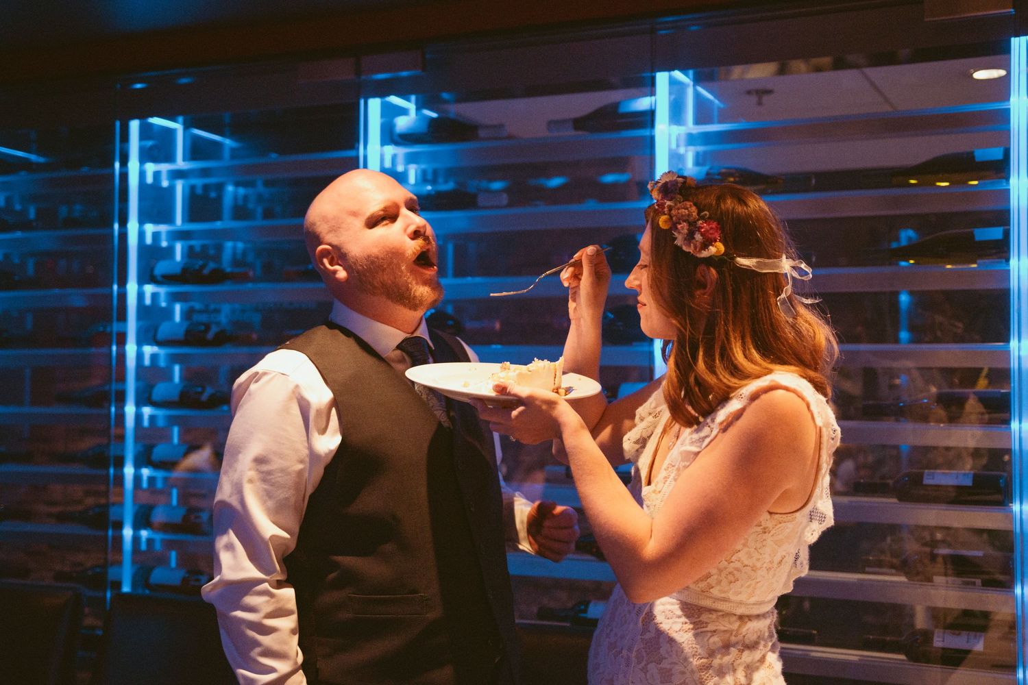 Wedding celebration with dancing couples under blue neon lighting at indoor venue.