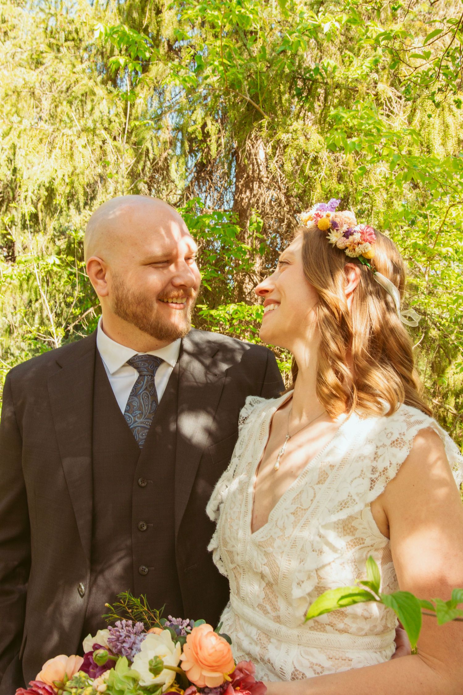 Romantic wedding portraits captured in a sunlit garden with lush greenery.