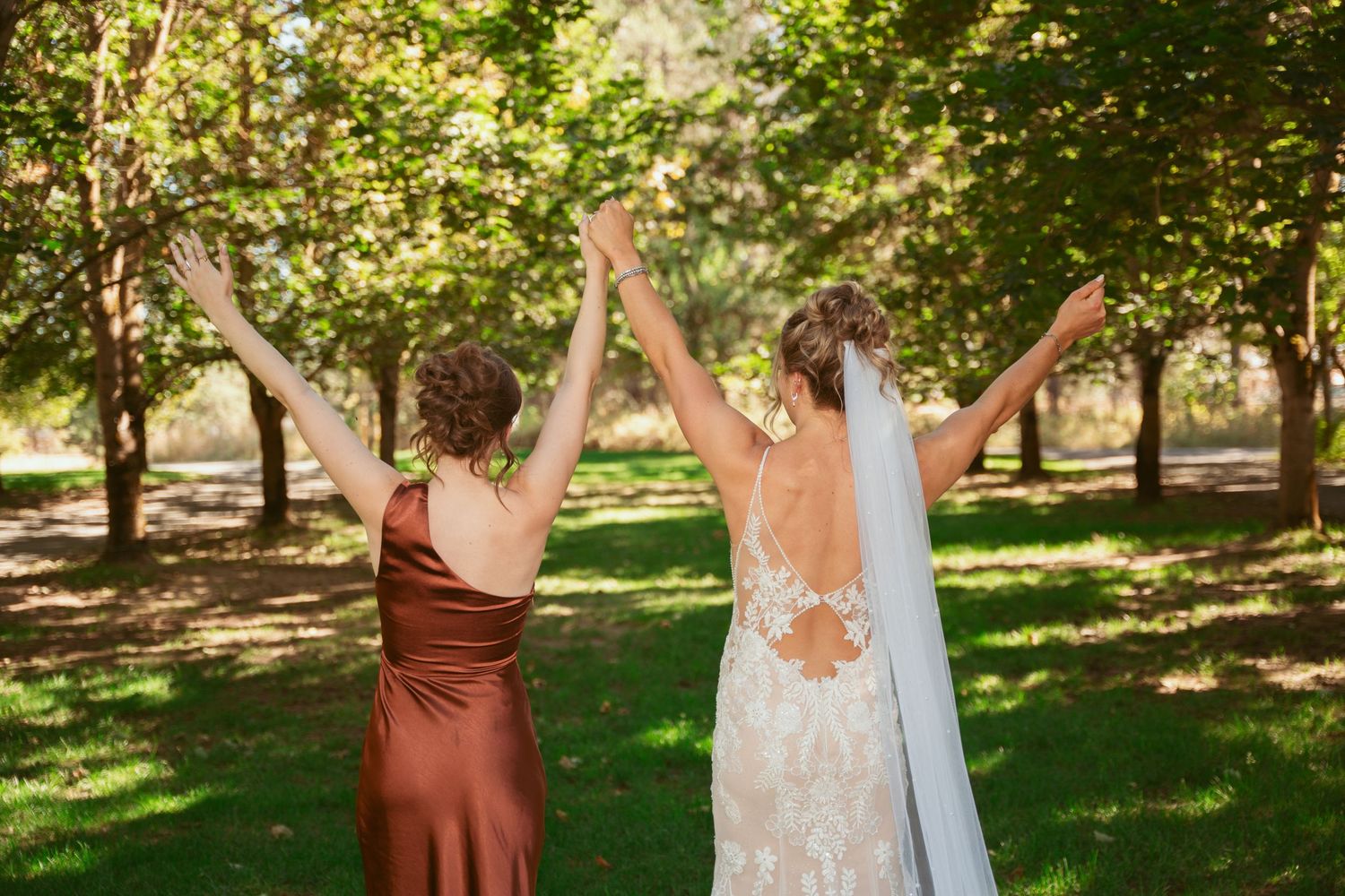 Wedding party members in burgundy and white dresses pose in an orchard.