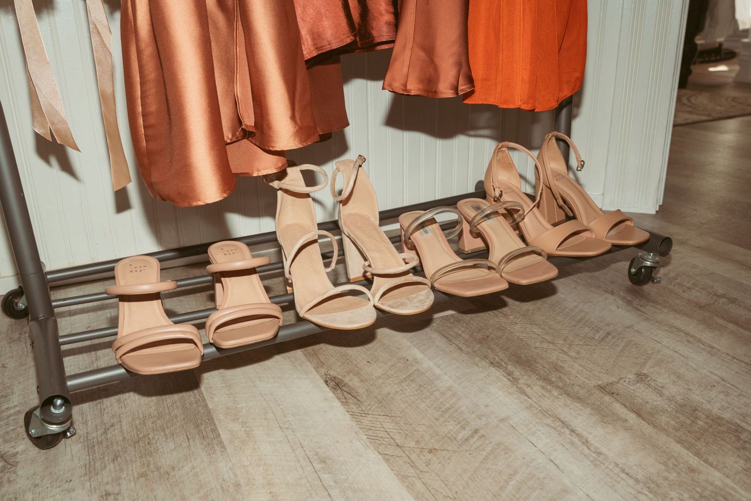 Rows of copper-colored dresses and sandals displayed on hangers and shelves in a boutique clothing store.