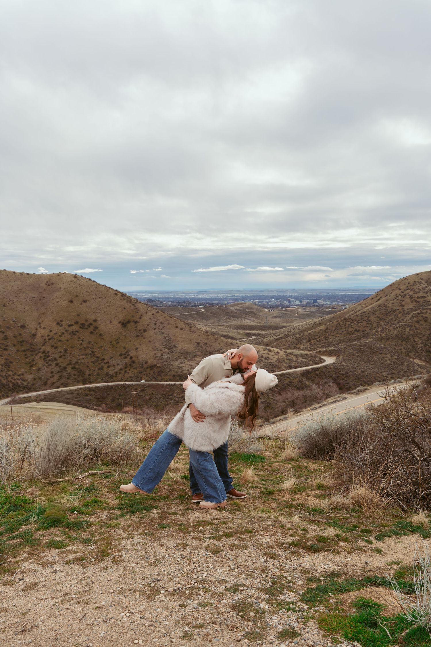 Couple sharing romantic dance moves on mountain trail with scenic valley views.
