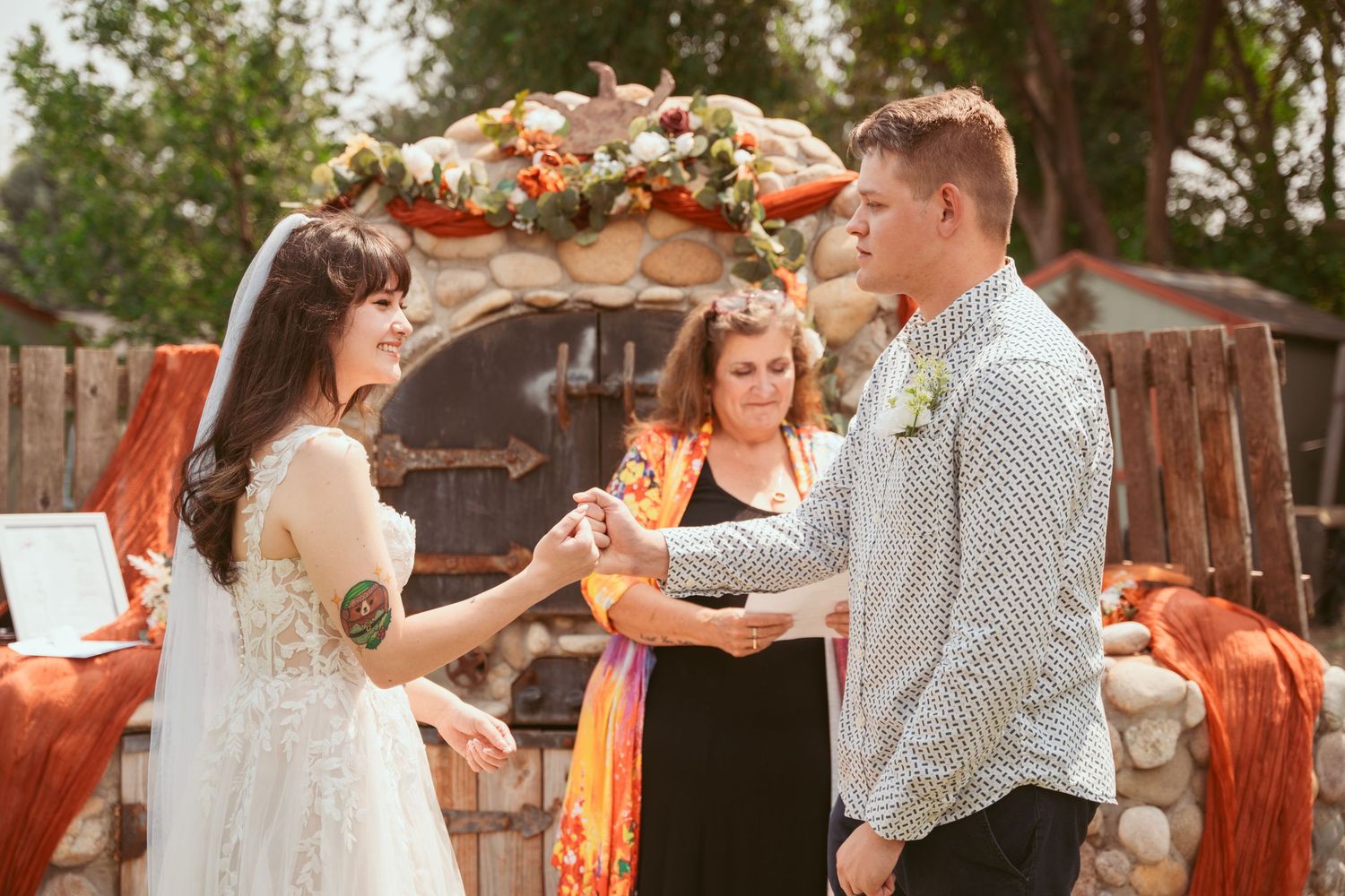 Couple dances together at an outdoor wedding reception with autumn-colored floral arrangements.