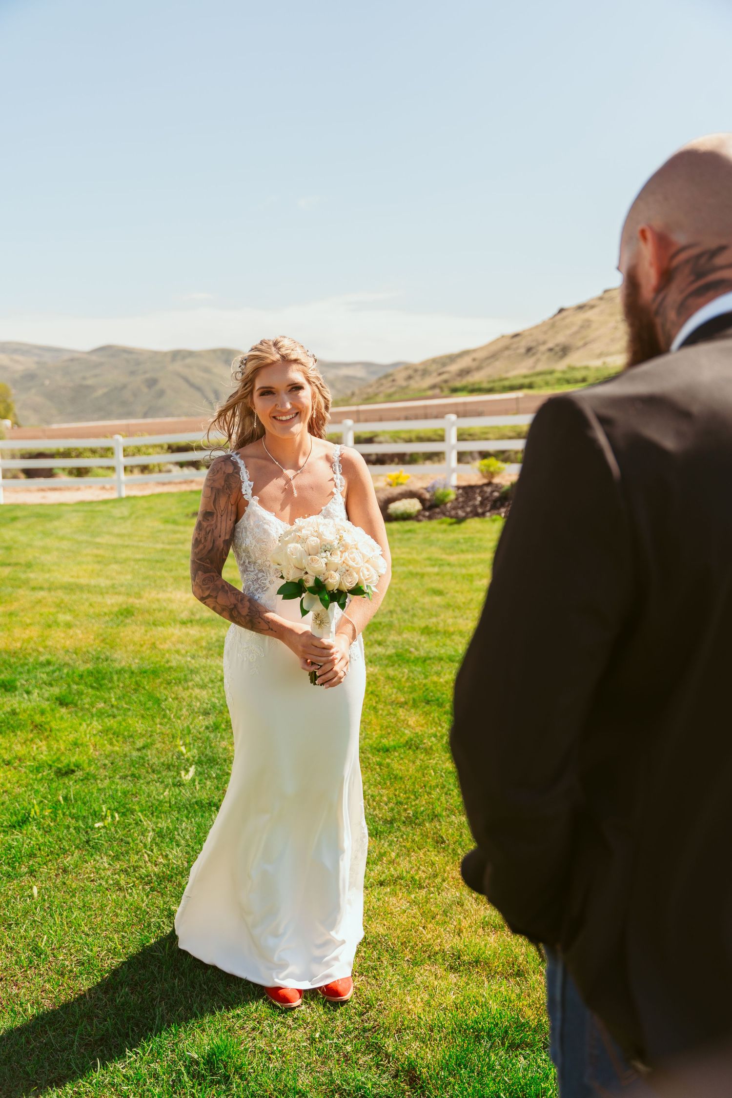 A couple shares a joyful moment during their wedding photoshoot in a rustic outdoor setting.