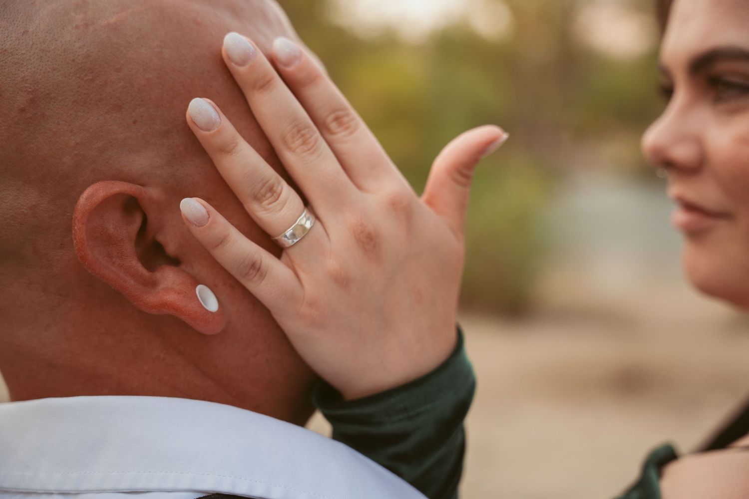 Close-up shot of a couple's tender moment with engagement ring visible.