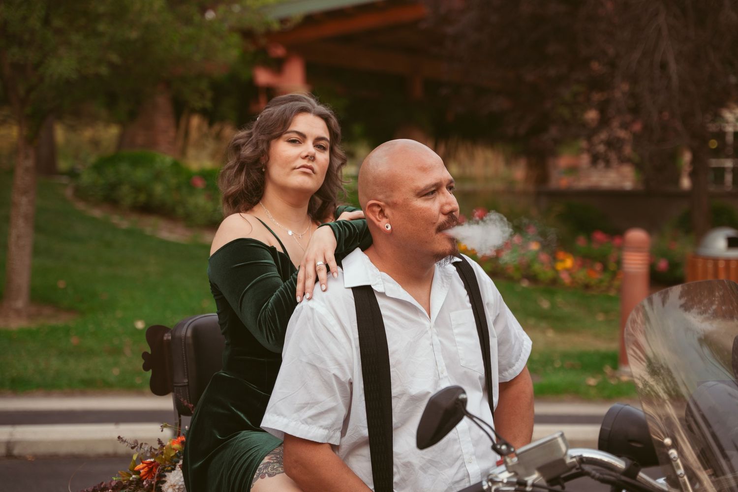 Romantic motorcycle photoshoot in a park setting with colorful flowers.
