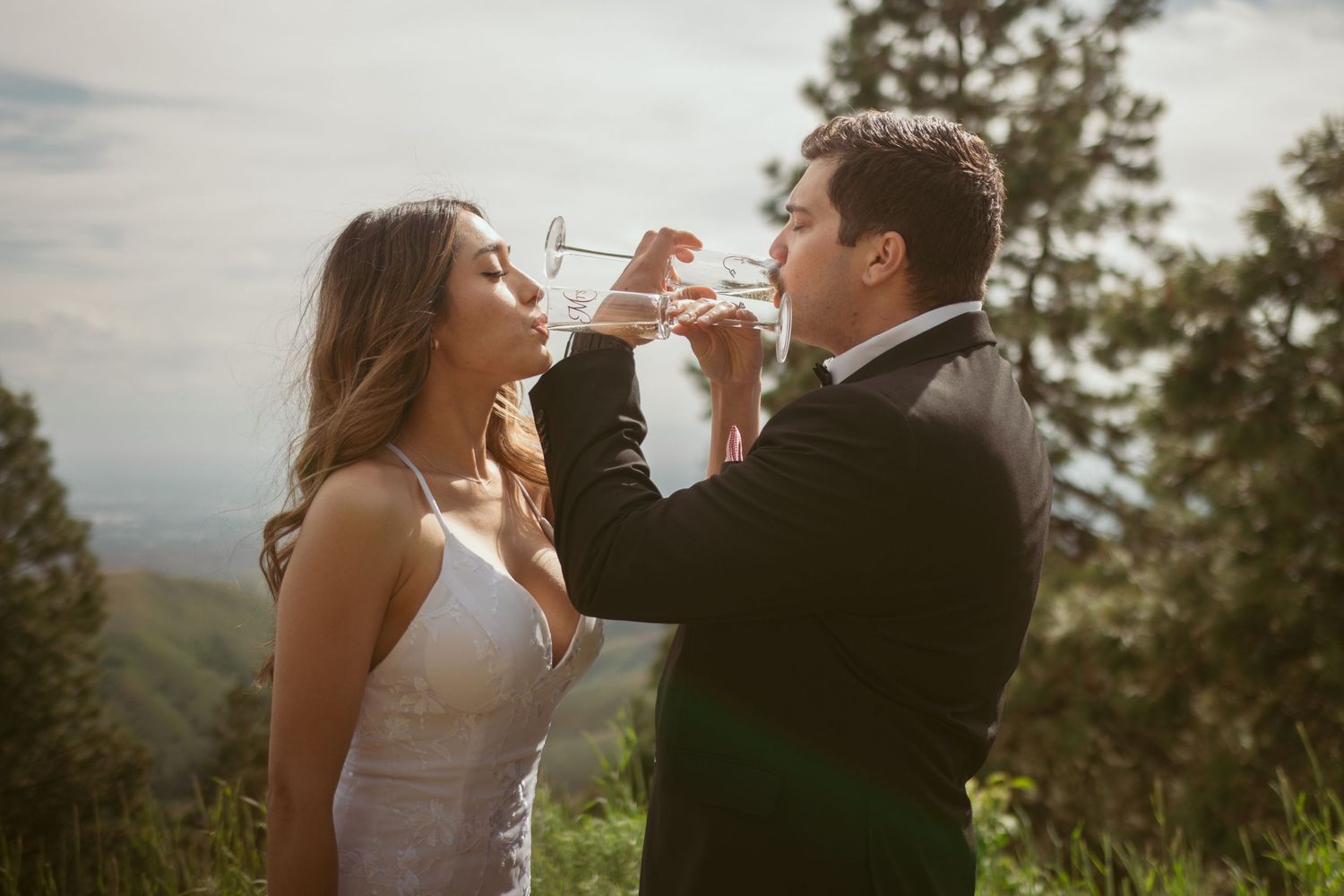 A couple shares a champagne toast during their mountain wedding celebration.