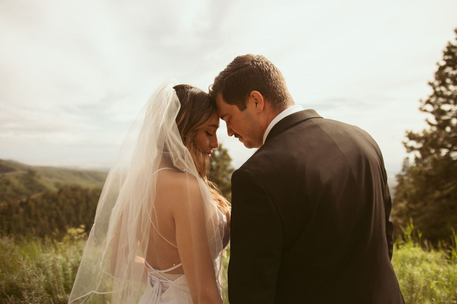 A tender moment between newlyweds during their mountain wedding ceremony at sunset.
