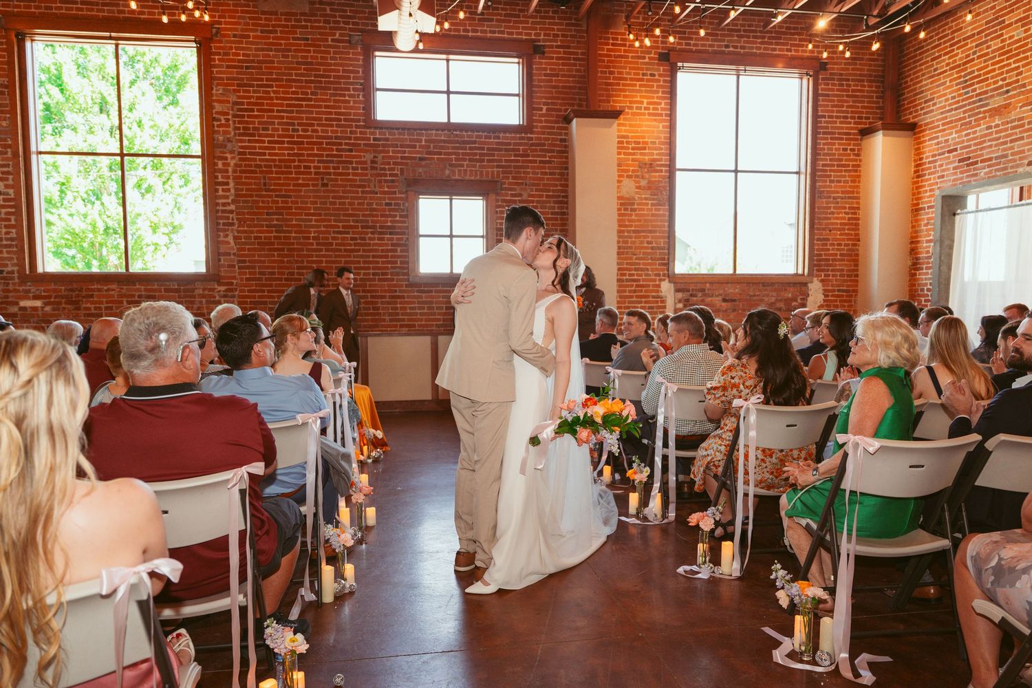 Wedding venue interior with exposed brick walls and white chairs set up for ceremony guests.