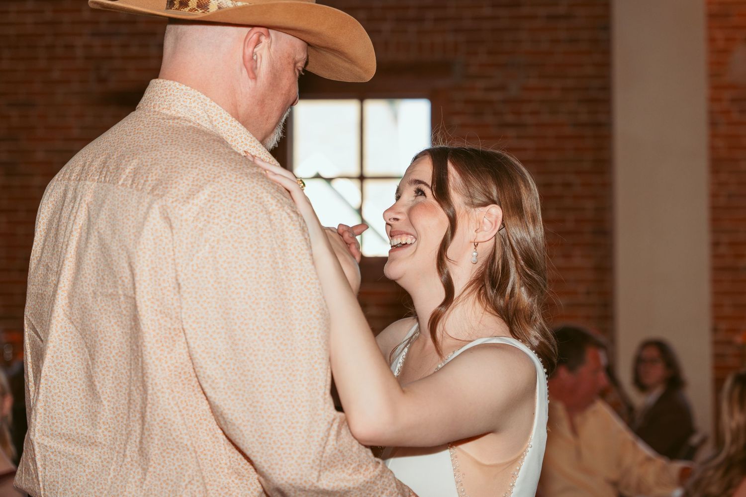 Intimate dance moment at a wedding reception in a brick-walled venue.
