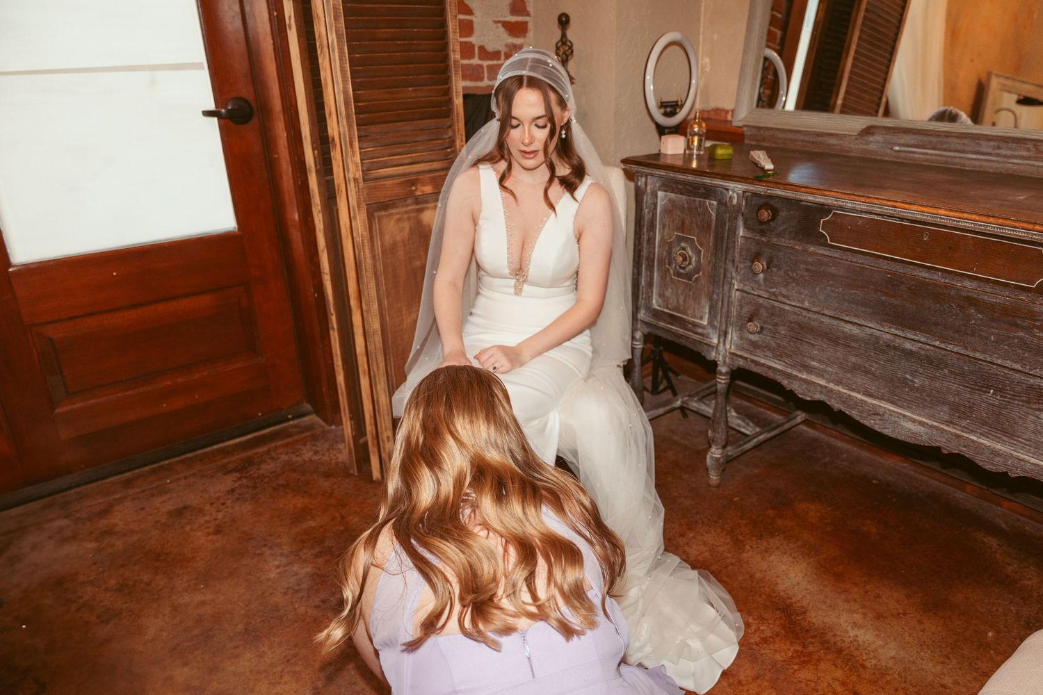 A bridal preparation moment captured in a vintage-style venue with exposed brick walls.