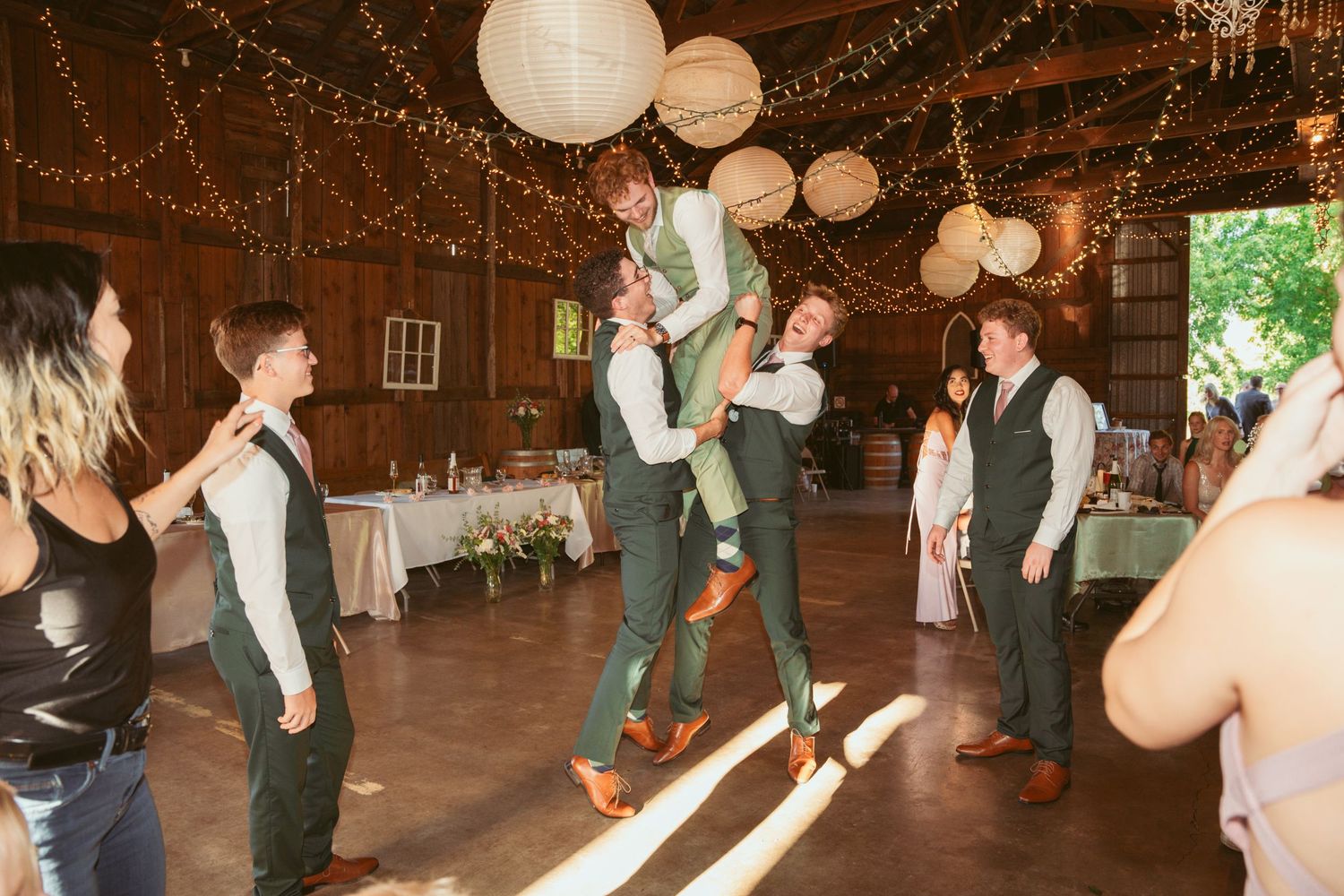 Guests performing synchronized dance moves at a rustic barn wedding reception.