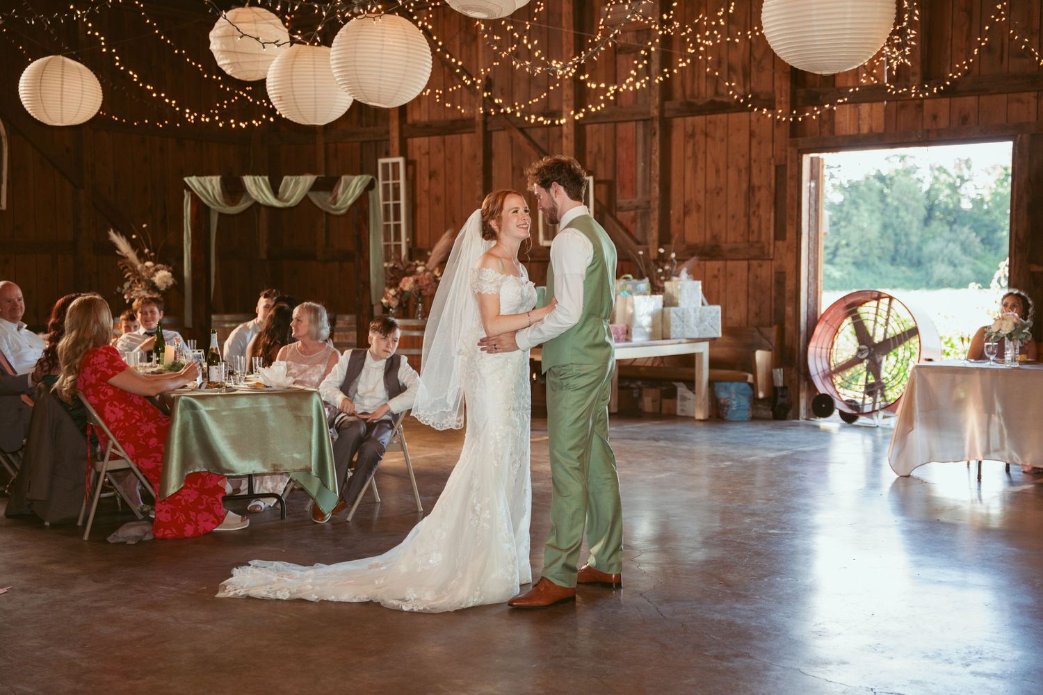 Wedding reception in a barn with elegant paper lantern and string light decorations.
