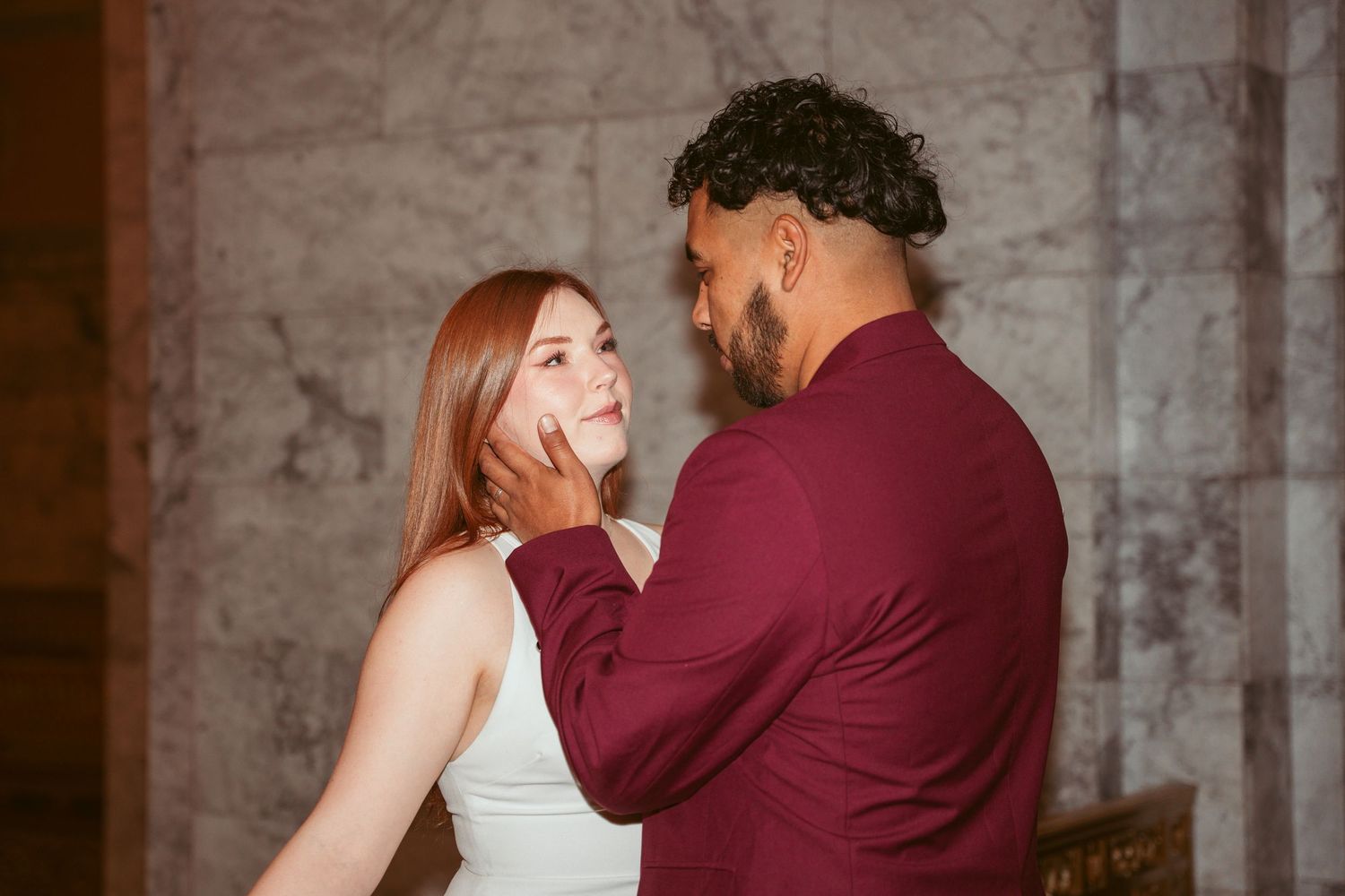 A couple shares playful and romantic moments along an elegant marble balcony.