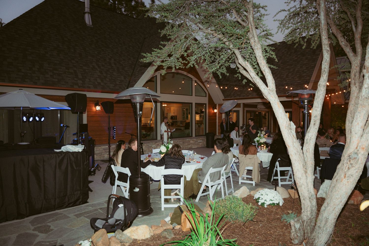 Evening garden party setup with illuminated string lights and white folding chairs.