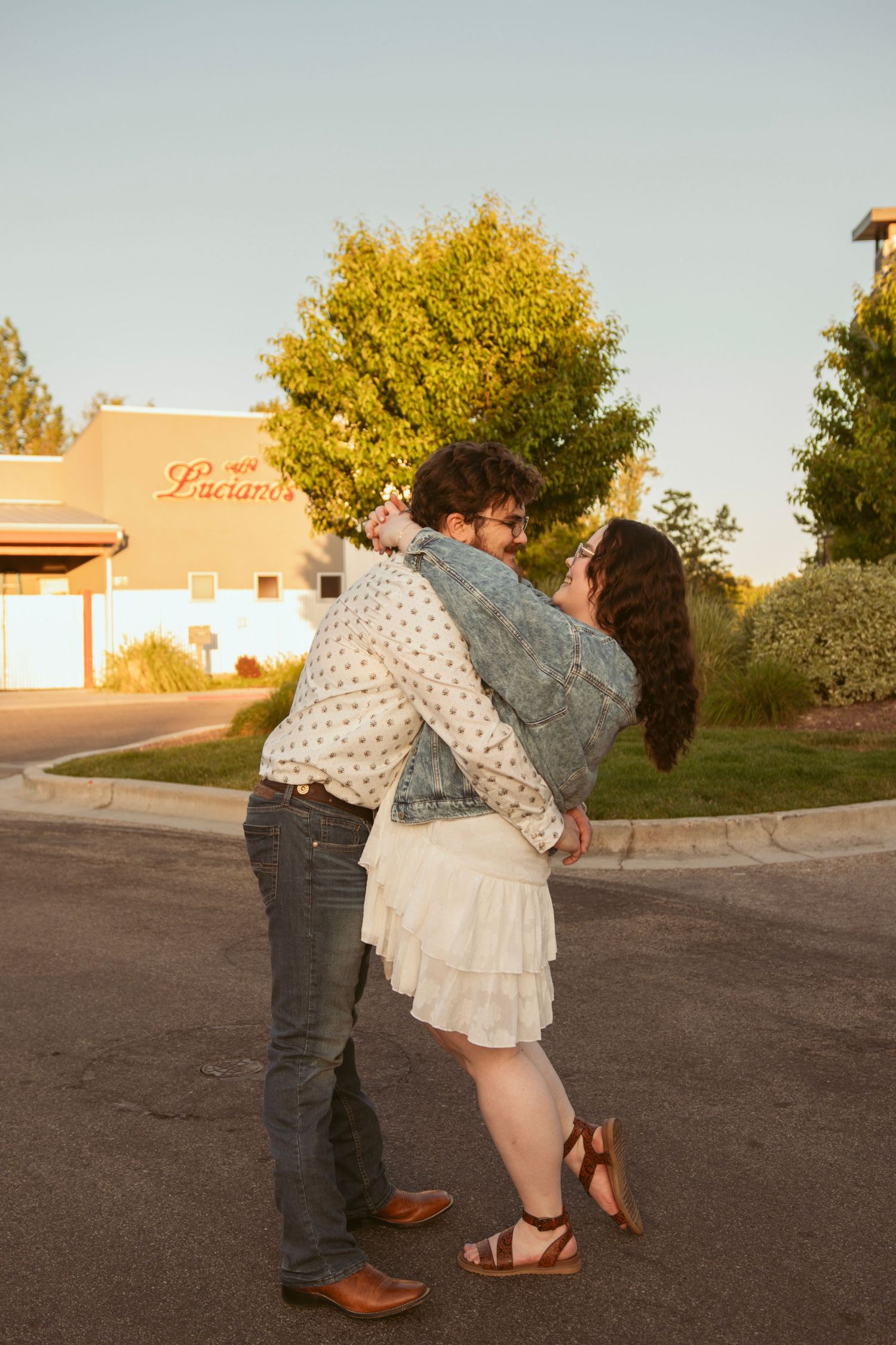 A joyful celebration between two people after getting engaged at sunset.