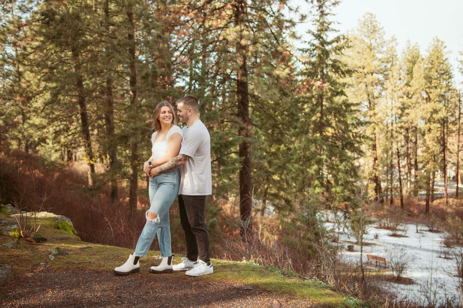 Scenic outdoor couples photoshoot among pine trees and snowy patches.