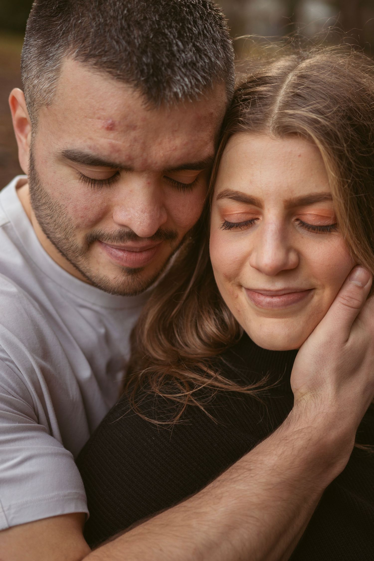 Tender moment between couple with eyes closed in soft natural lighting.