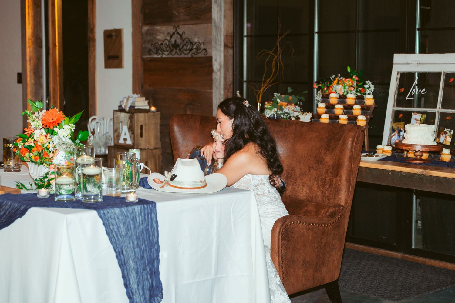 Wedding reception table setting with navy and white linens and floral centerpieces.