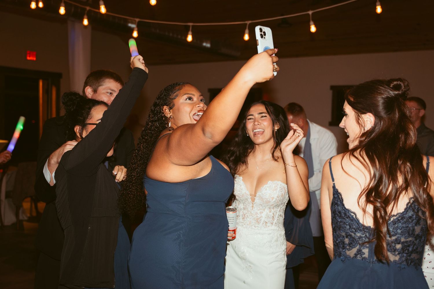 Festive crowd enjoying themselves on a dance floor under string lights.