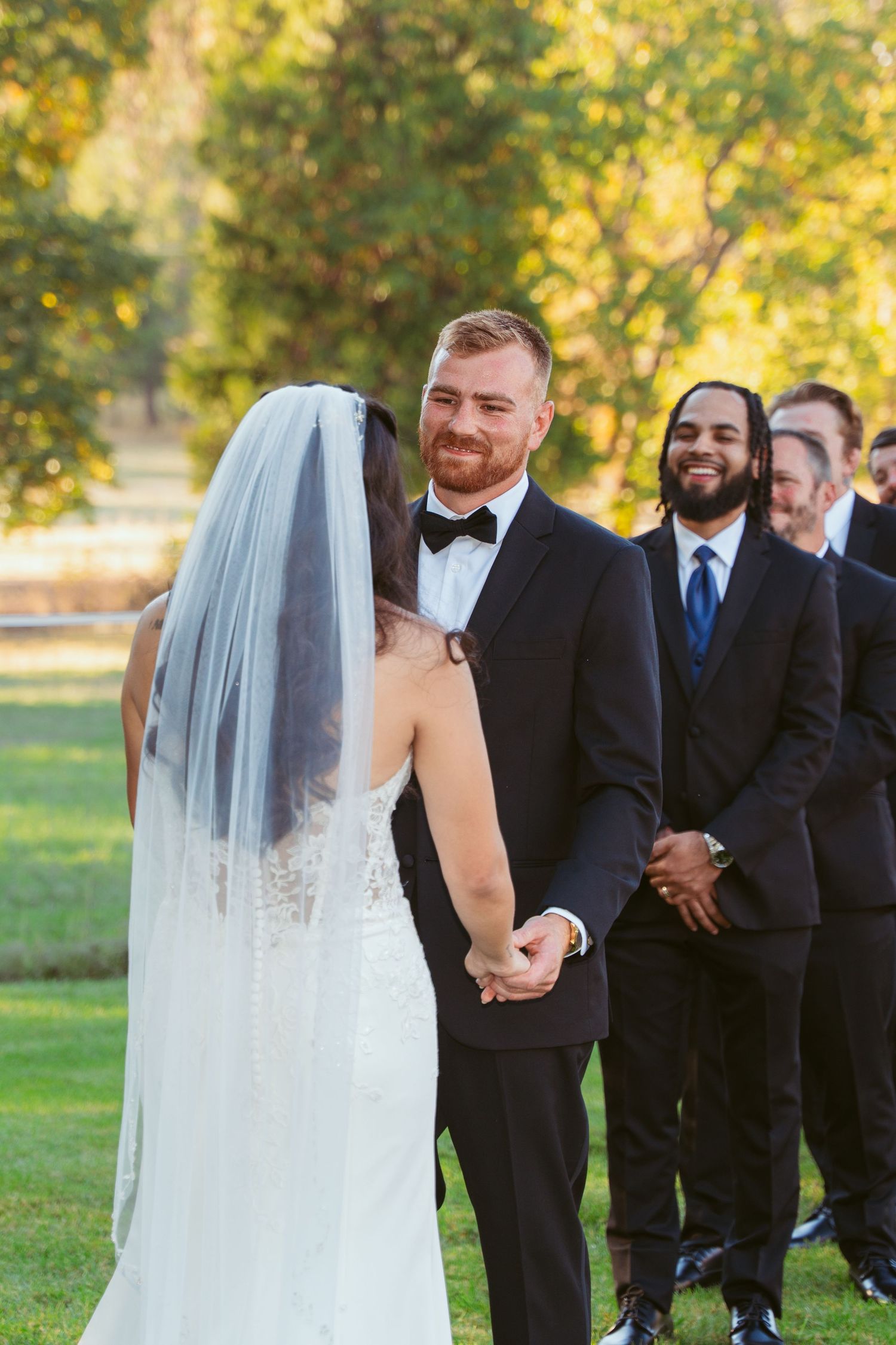 A tender moment during an outdoor wedding ceremony with autumn trees in the background.