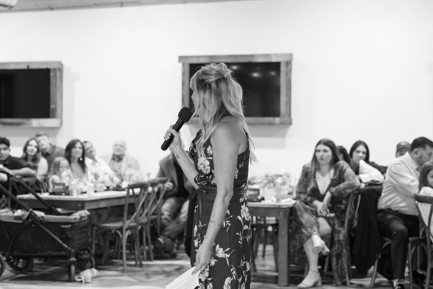 Wedding reception venue with white walls and guests seated at long tables for dinner.