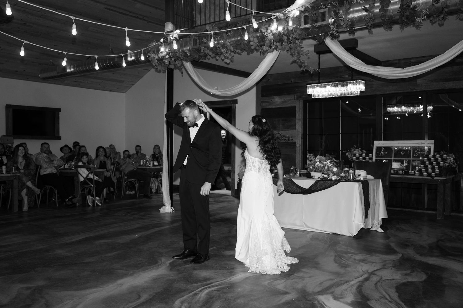 Dance floor scene at wedding reception with string lights overhead creating romantic atmosphere.
