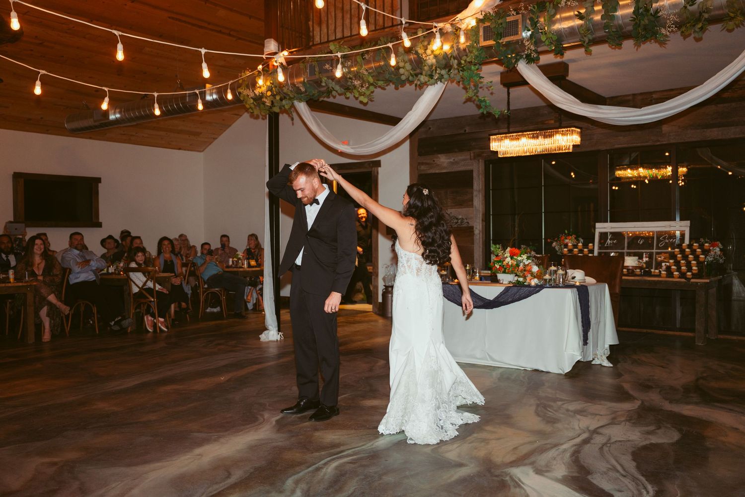 A couple performs a dramatic dance dip on an illuminated dance floor at a wedding reception.