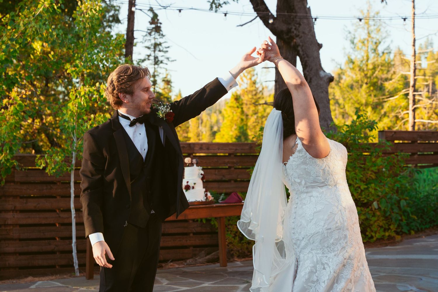 A couple performs their wedding dance on a stone patio surrounded by autumn trees.