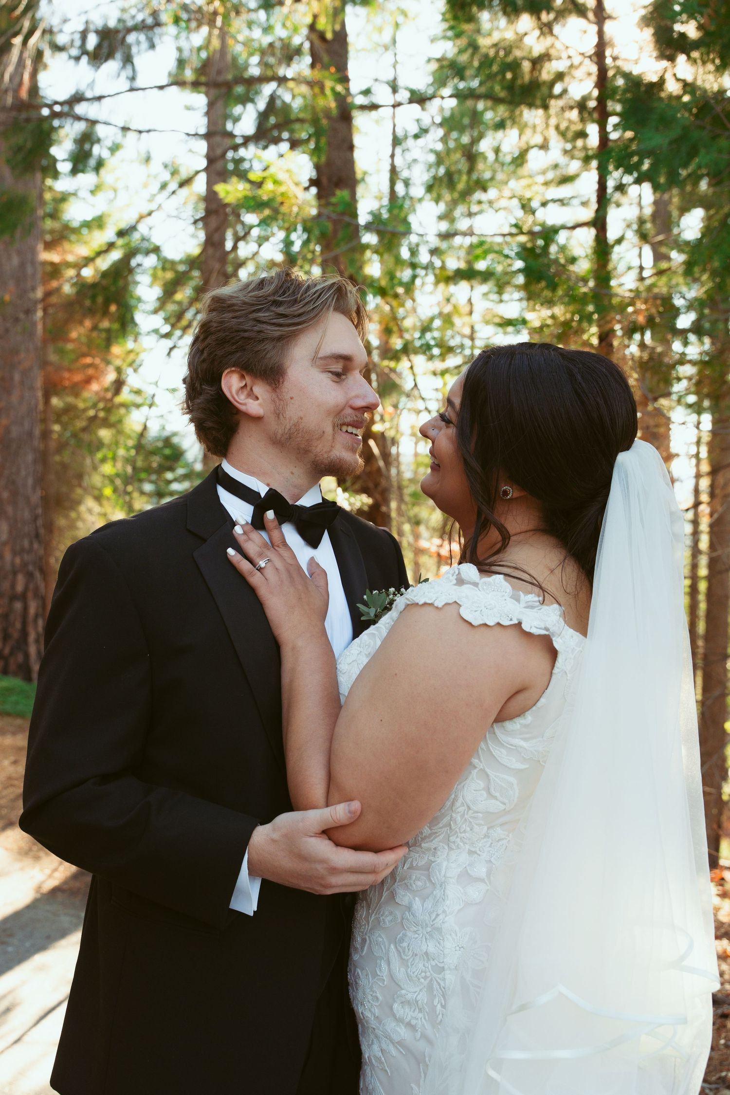 A tender moment between newlyweds surrounded by golden sunlight filtering through forest trees.