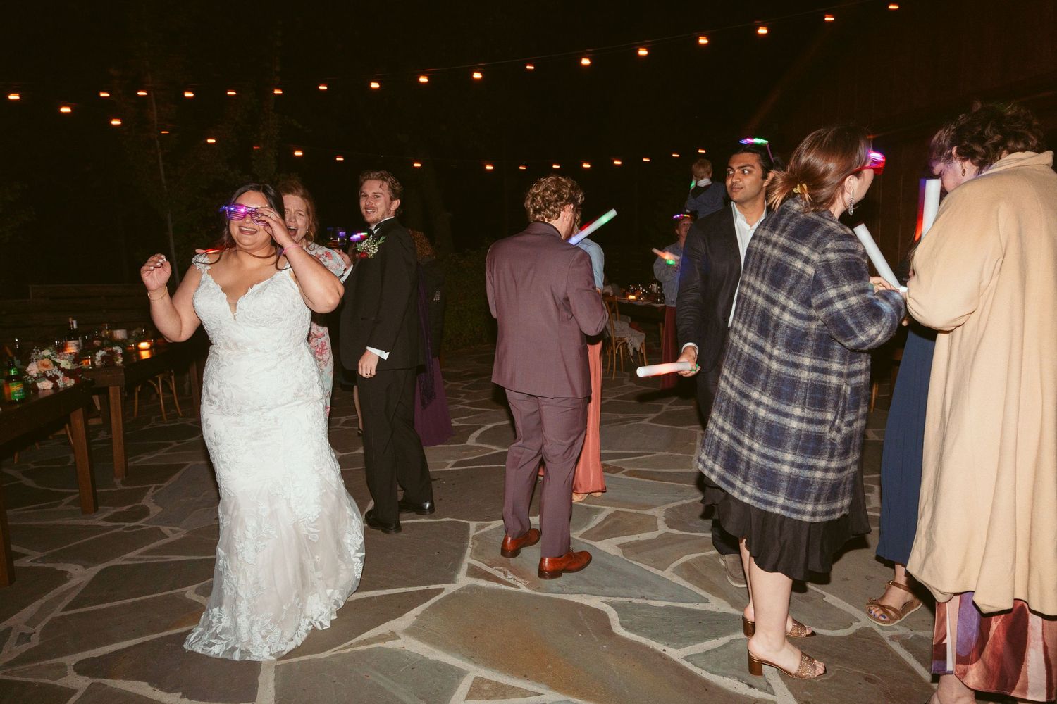 Wedding guests dancing on a patterned floor at an outdoor evening reception.