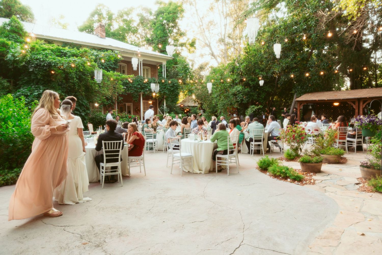 Guests seated at round tables during a sunset garden wedding reception.