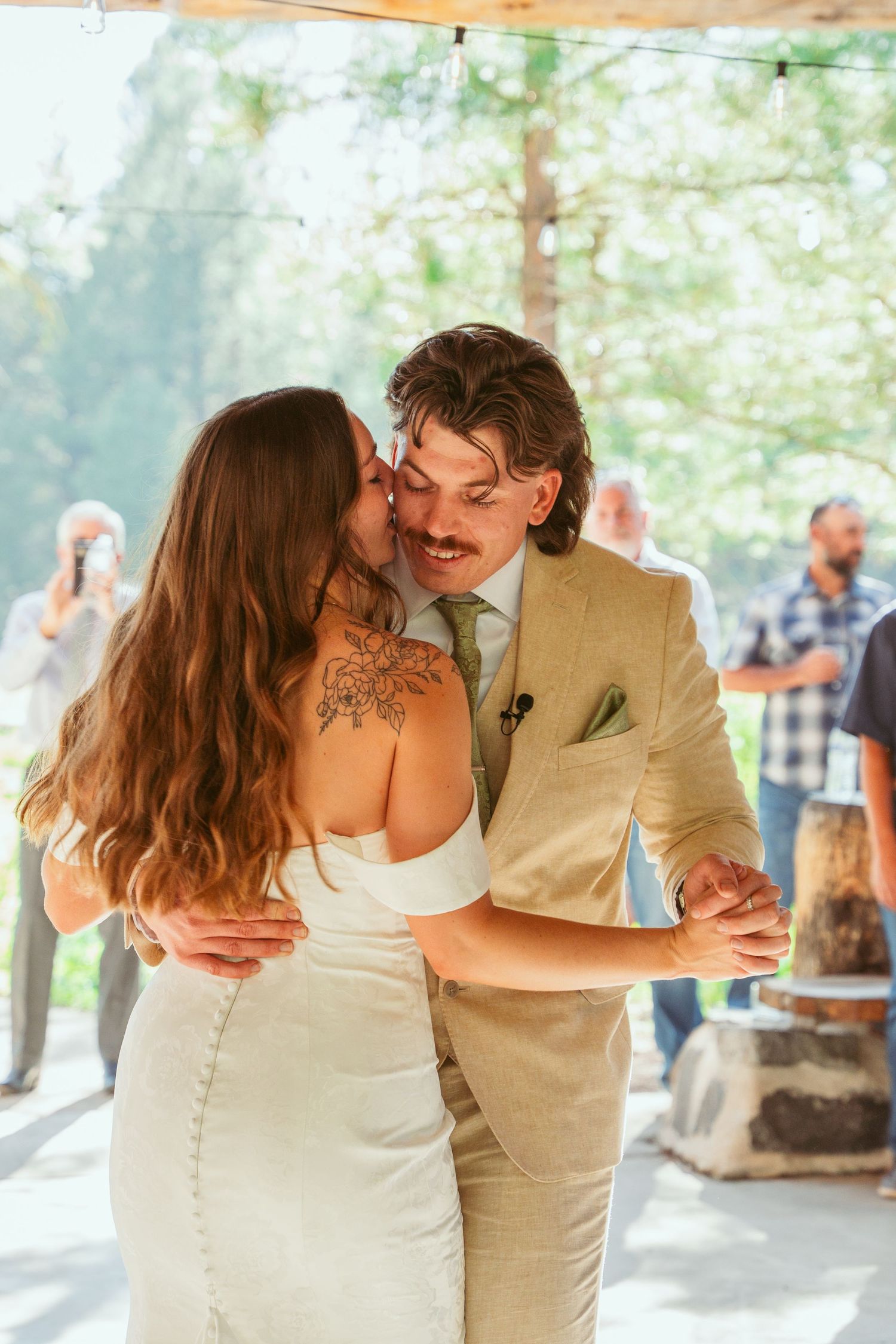 Intimate moment between dancing newlyweds in rustic outdoor wedding venue.