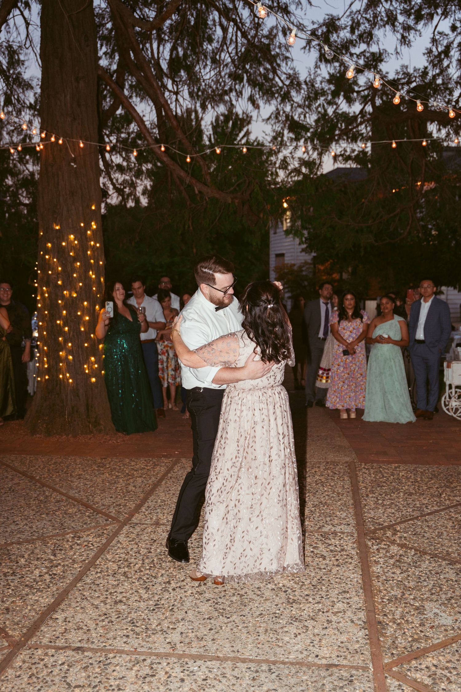 Guests share romantic dances on an outdoor dance floor decorated with string lights.