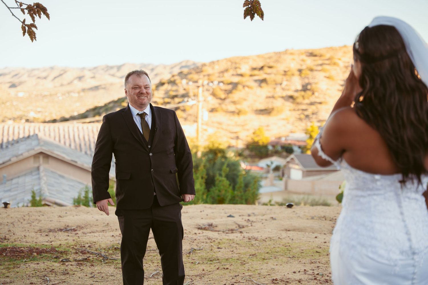A couple shares a romantic moment outdoors with desert hills visible in the background.