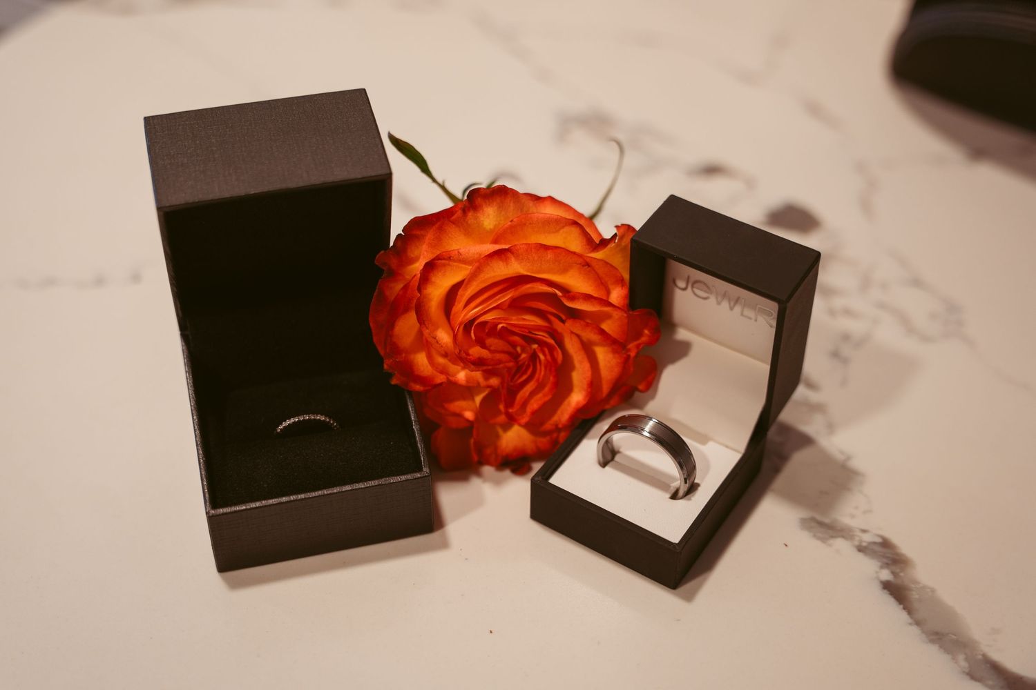 Multiple black jewelry boxes arranged with orange roses on a white surface.