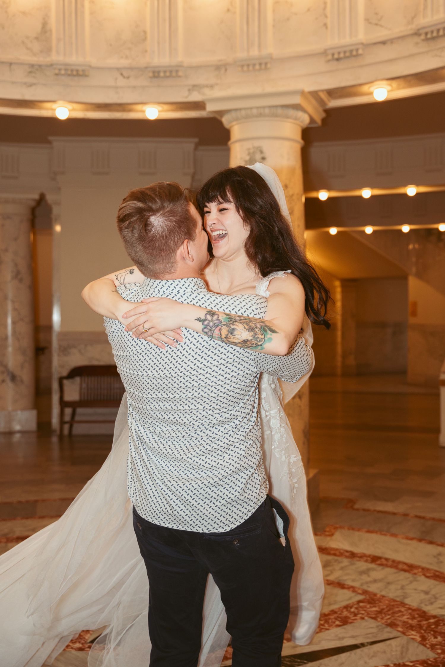 A couple dances together in an elegant ballroom with ornate architectural details.