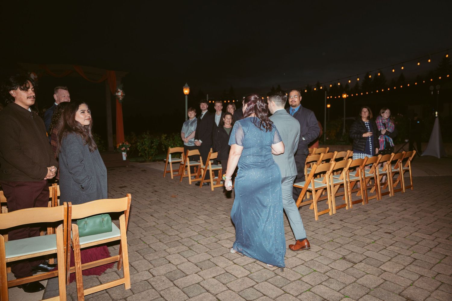 Evening event space with wooden chairs and string lights creating a cozy atmosphere.