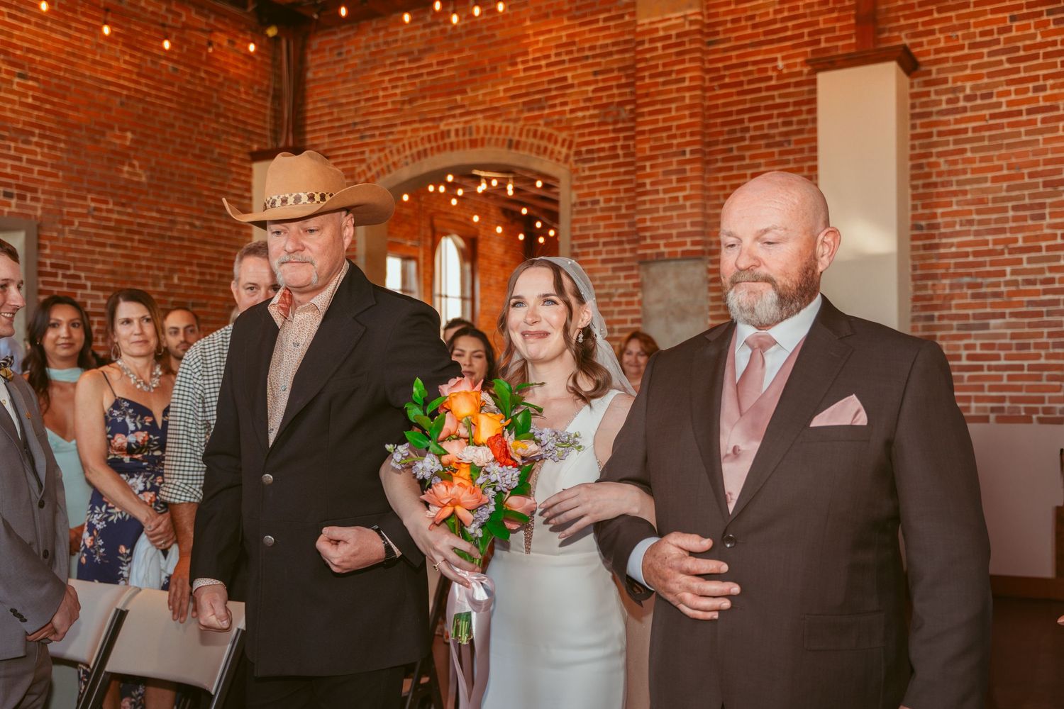 Wedding celebration in a rustic brick venue with string lights overhead.