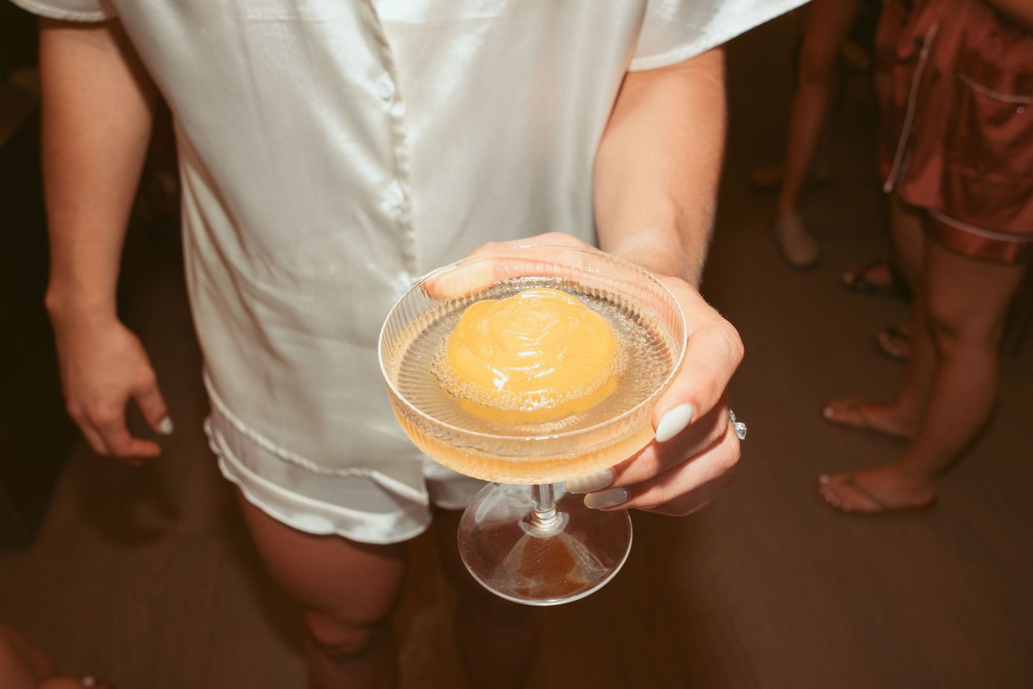 A series of hands holding martini glasses with creamy cocktails featuring latte art designs on top.