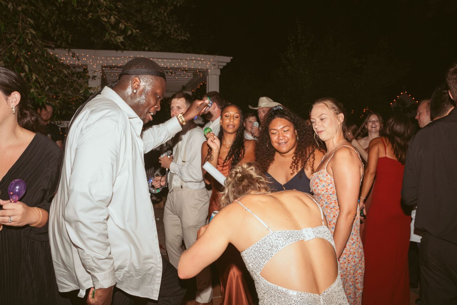 Guests dancing and celebrating at a dimly lit outdoor wedding venue.