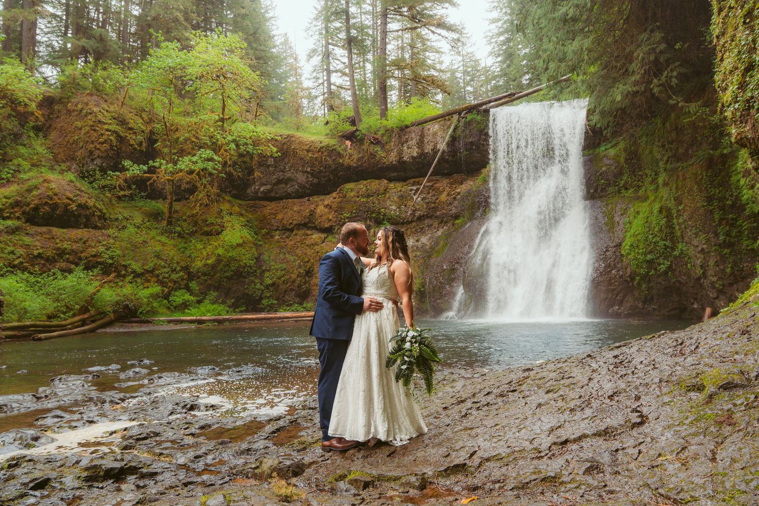 Wedding ceremony photos captured against the backdrop of a scenic forest waterfall.