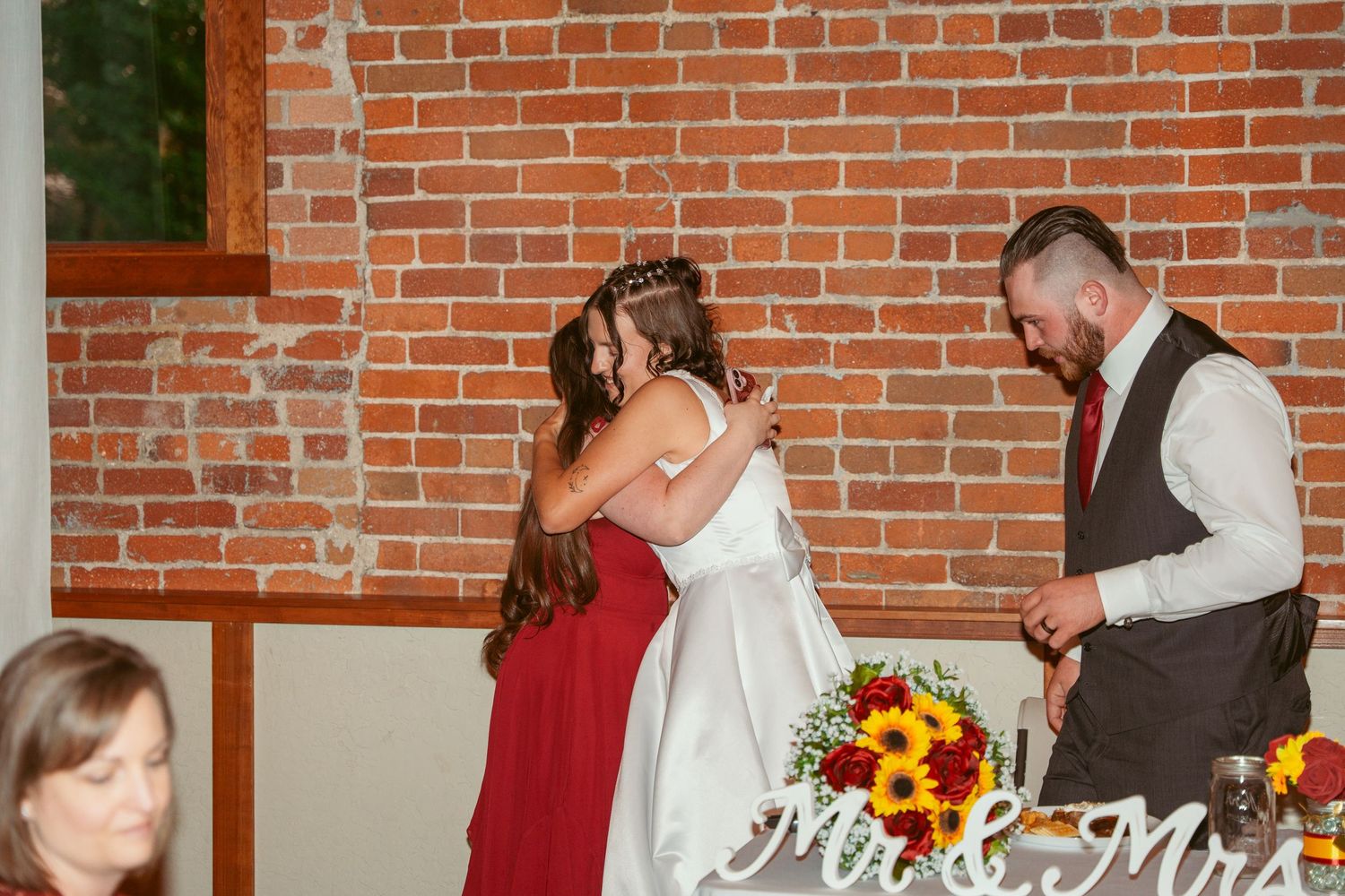 Wedding celebration in rustic brick venue with sunflower accents and white table settings.