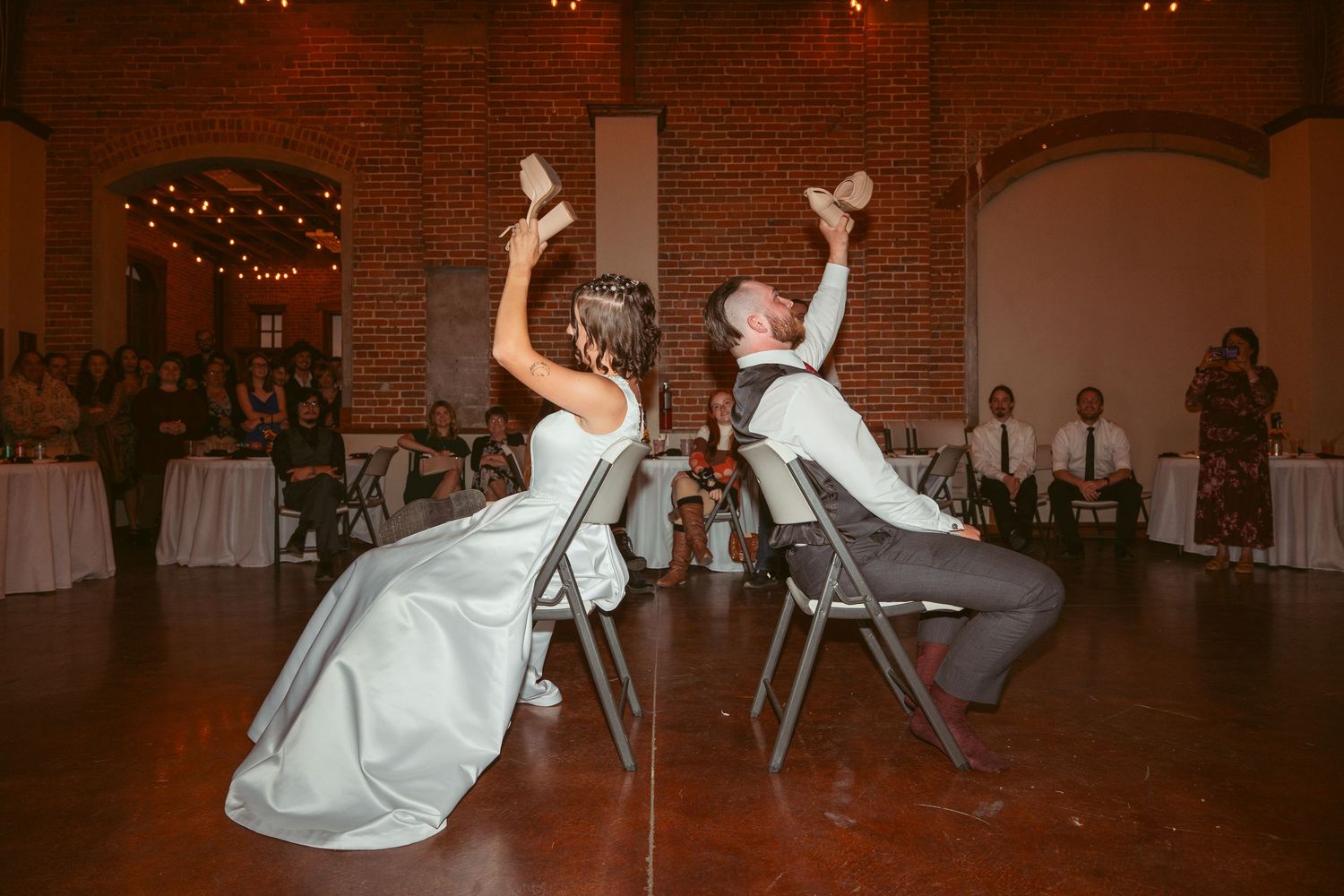 Group dancing sequence shows energetic moves on a hardwood floor at an indoor wedding venue.