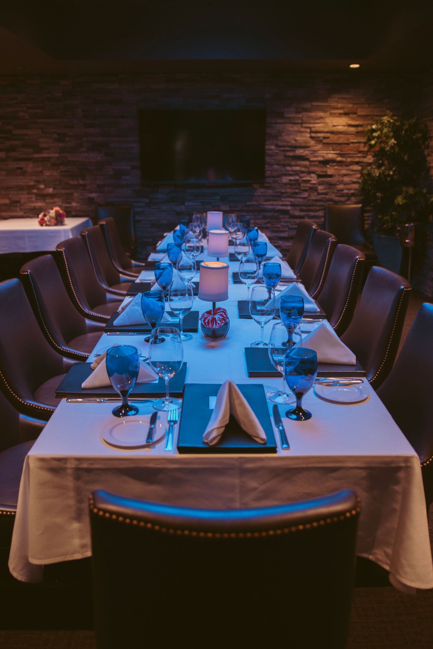 Elegant dining table set with blue lighting and formal place settings in a restaurant.