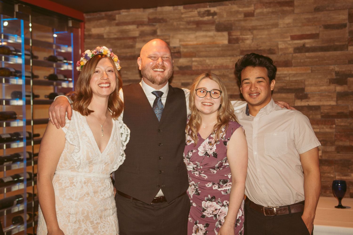 Guests gather for group photos in a rustic venue with wooden wall paneling.